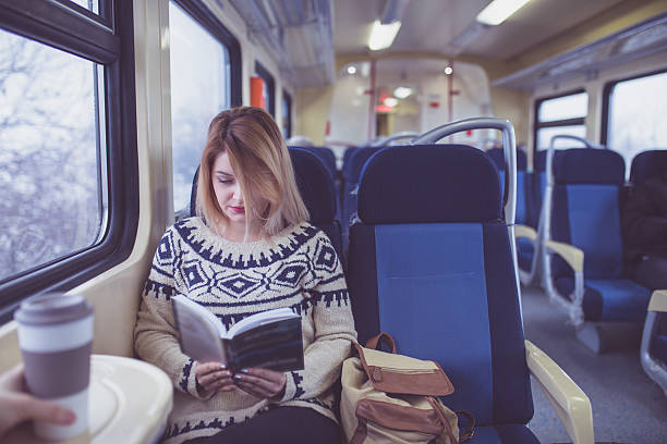 istock Young woman reading a book while on a train 637555534