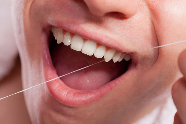 istock Young man cleaning her white teeth with dental floss 637564200