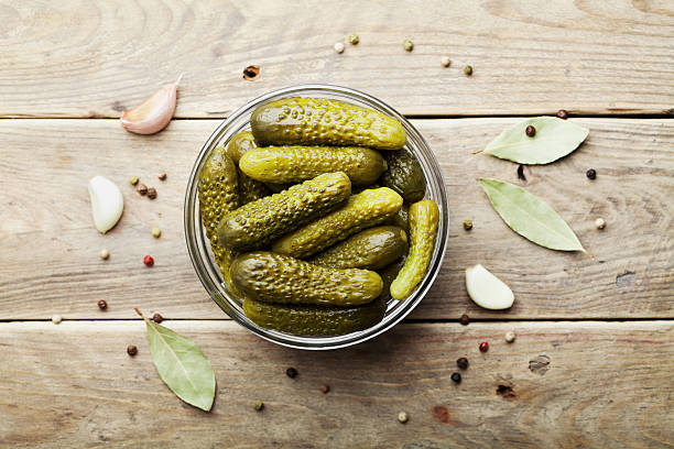 gherkins em conserva ou pepinos em mesa rústica de madeira. leigos planos. - salted - fotografias e filmes do acervo