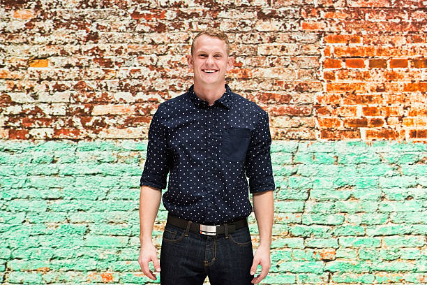istock Smiling man in front of brick wall 637569506