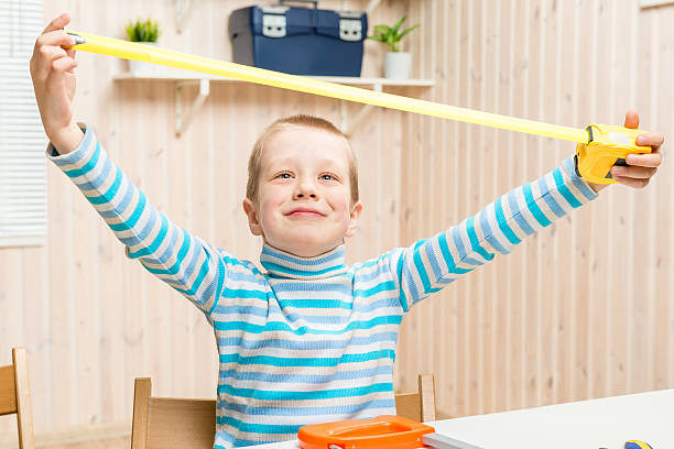 istock 6 years old boy in the garage with measuring tape 637570260