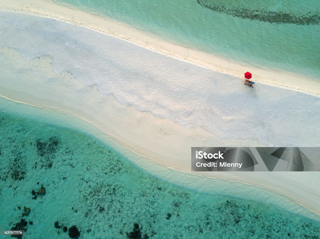 Aerial Lonely Red Umbrella Beach Maldives South Ari Atoll Lonely red umbrella at the beautiful beach of a small tiny  Islet in the South Ari Atoll Area. Aerial Drone 90 Degrees Down View. South Ari Atoll, Republic of Maldives Maldives Stock Photo