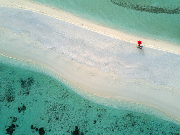 Aerial Lonely Red Umbrella Beach Maldives South Ari Atoll Lonely red umbrella at the beautiful beach of a small tiny  Islet in the South Ari Atoll Area. Aerial Drone 90 Degrees Down View. South Ari Atoll, Republic of Maldives atoll stock pictures, royalty-free photos & images