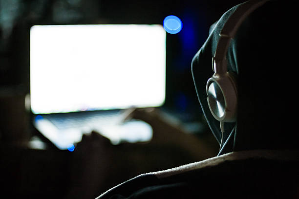 Computer hacker working on laptop in the dark stock photo