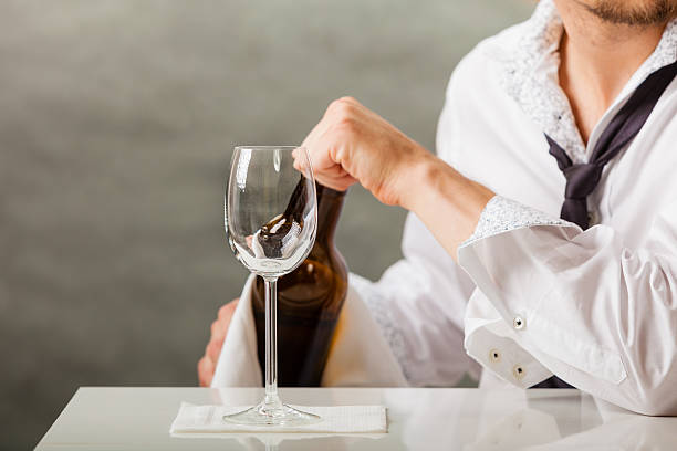 istock Man waiter pouring wine into glass. 637575438