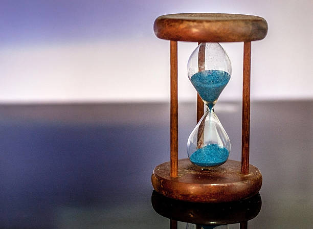istock Hourglass reflecting on glass table with colorful blue background 637585258