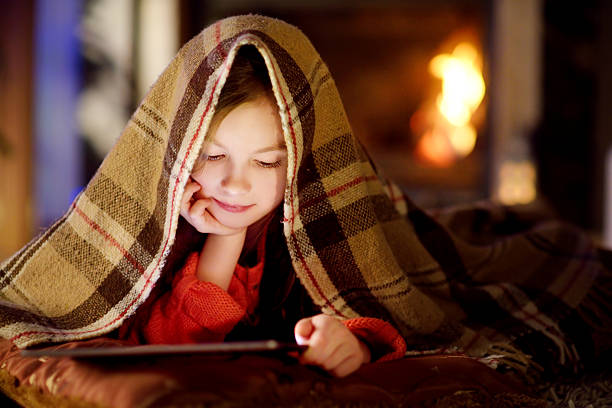 istock Adorable little girl using tablet by fireplace on Christmas evening 637587988