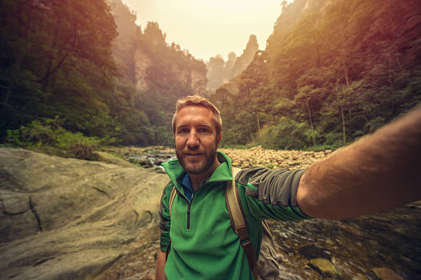 istock Young man hiking takes smart phone selfie, China 637588484
