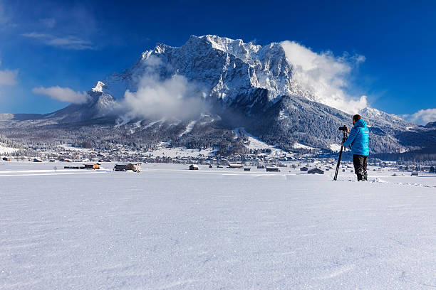 fotógrafo da natureza no inverno em frente ao monte zugspitze - zugspitze mountain tirol lermoos ehrwald - fotografias e filmes do acervo