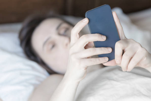 istock Woman Lying on Bed Checking Her Phone 637595730