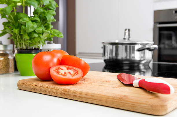 istock Sliced tomatoes on wooden cutting board in modern kitchen 637599494