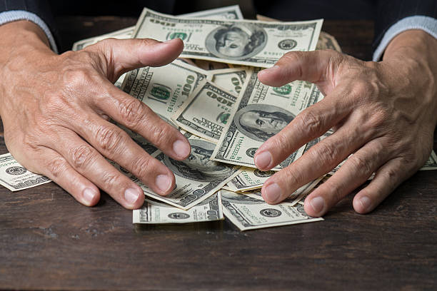 manos del hombre barriendo dinero, concepto de negocio. - codicia fotografías e imágenes de stock