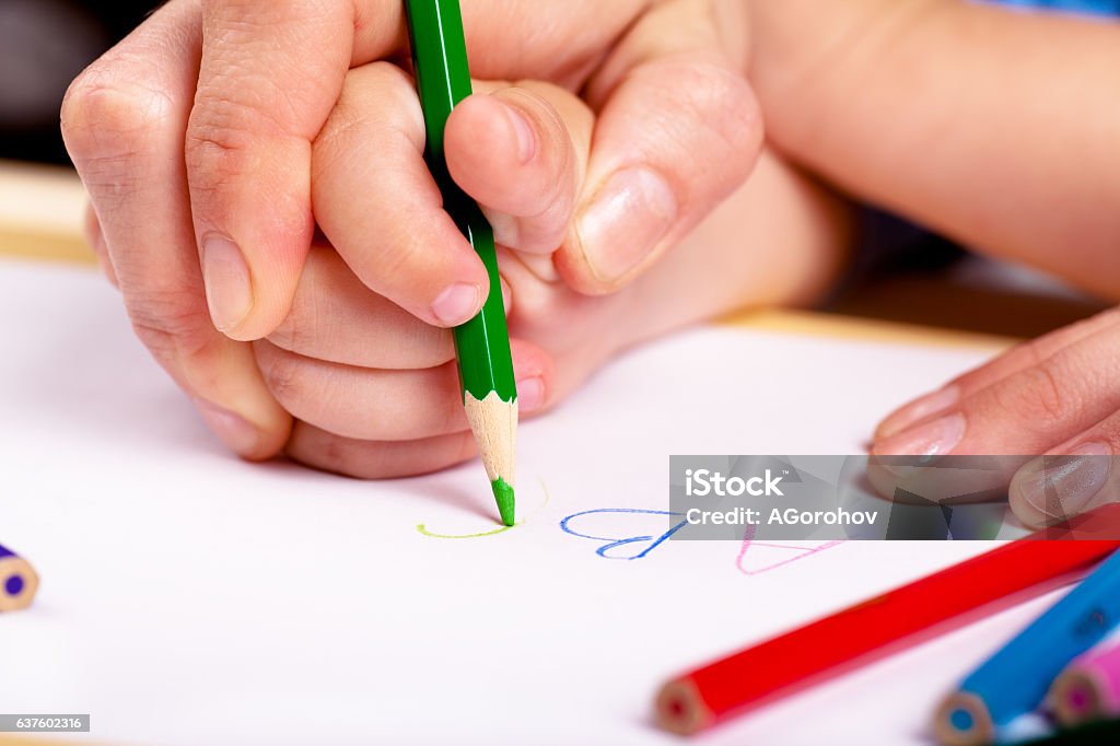 Learn to write Child hand with pencil and woman hand helping to write letters Child Stock Photo