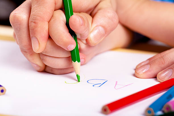Learn to write Child hand with pencil and woman hand helping to write letters alphabetical order photos stock pictures, royalty-free photos & images