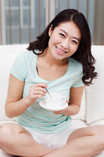 istock Young woman sitting on a couch,holding coffee cup 637605912