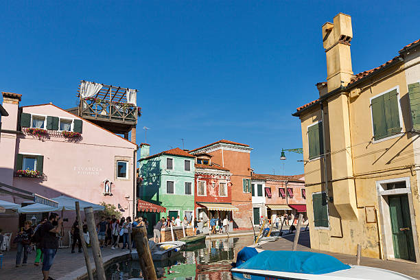 paseo turístico a lo largo del canal típico en la isla de burano, italia. - chimney lagoon island canal fotografías e imágenes de stock