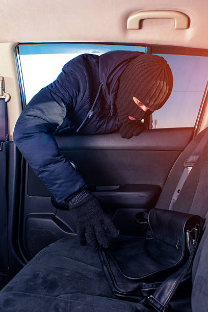 istock Robber in black mask stealing bag from car 637608748