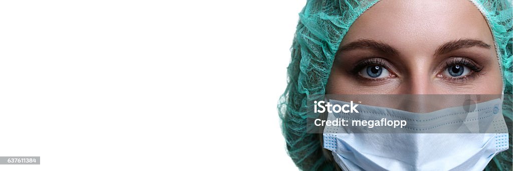 Female doctor face wearing protective mask and green surgeon cap Female doctor face wearing protective mask and green surgeon cap closeup isolated on white background. Save patient life, copy space banner, laboratory, 911, medic help concept. Letterbox view Surgeon Stock Photo