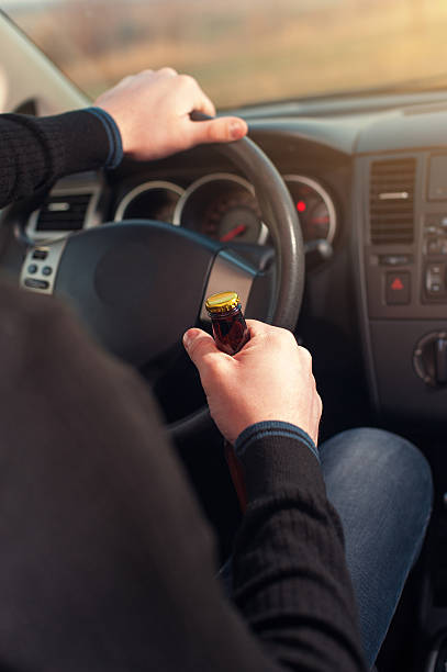 istock Closeup of man driving a car while drinking beer 637612134
