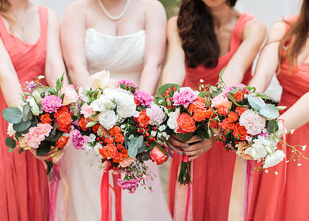 Bridesmaids and bride holds bouquets in hand. stock photo