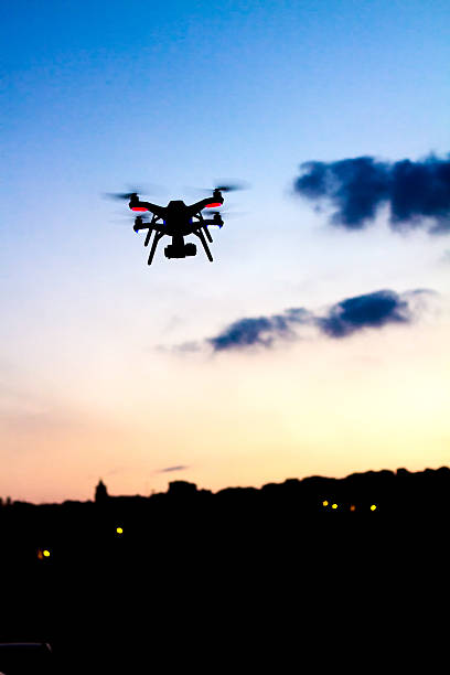 istock Small Drone with Camera Flies At Sunset, Skyline in Distance 637622634