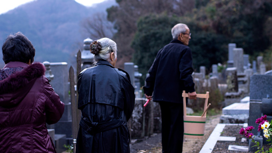 There are three senior Japanese people visiting their graves in Japan.