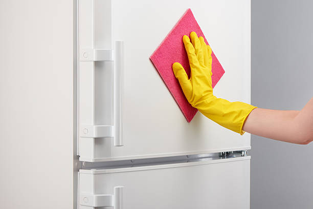 istock Hand in yellow glove cleaning white refrigerator with pink rag 637638626