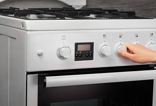 istock Female hand turning on white kitchen gas stove on gray 637639324