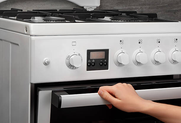 istock Female hand opening oven in white kitchen gas stove 637639368