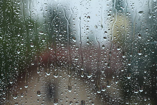 istock Rain drops on window with house and church in background 637639624