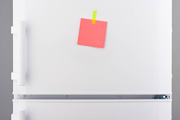 istock Pink note attached with yellow sticker on white refrigerator 637639760