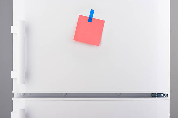 istock Pink paper note attached with blue sticker on white refrigerator 637639828