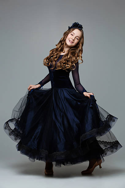 Beautiful teenage ballroom dancer Beautiful teenager ballroom dancer with long blond hair in long dark blue dress making curtsy. Studio shot on grey background. Copy space. curtseying stock pictures, royalty-free photos & images
