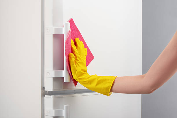 istock Hand in yellow glove cleaning white refrigerator with pink rag 637640544