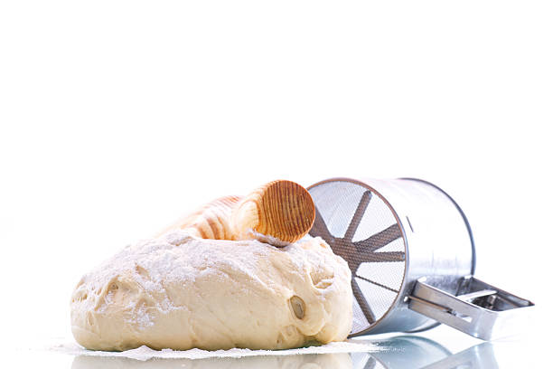 yeast dough with a wooden rolling pin on a white background