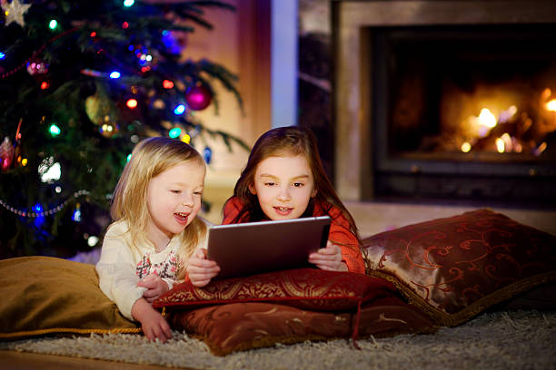 istock Two cute little sisters using tablet by fireplace on Christmas 637645520
