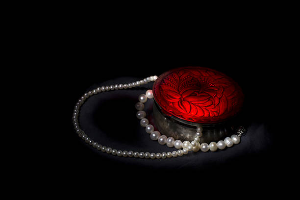 istock Silver box with red lid and pearls on black background 637645692