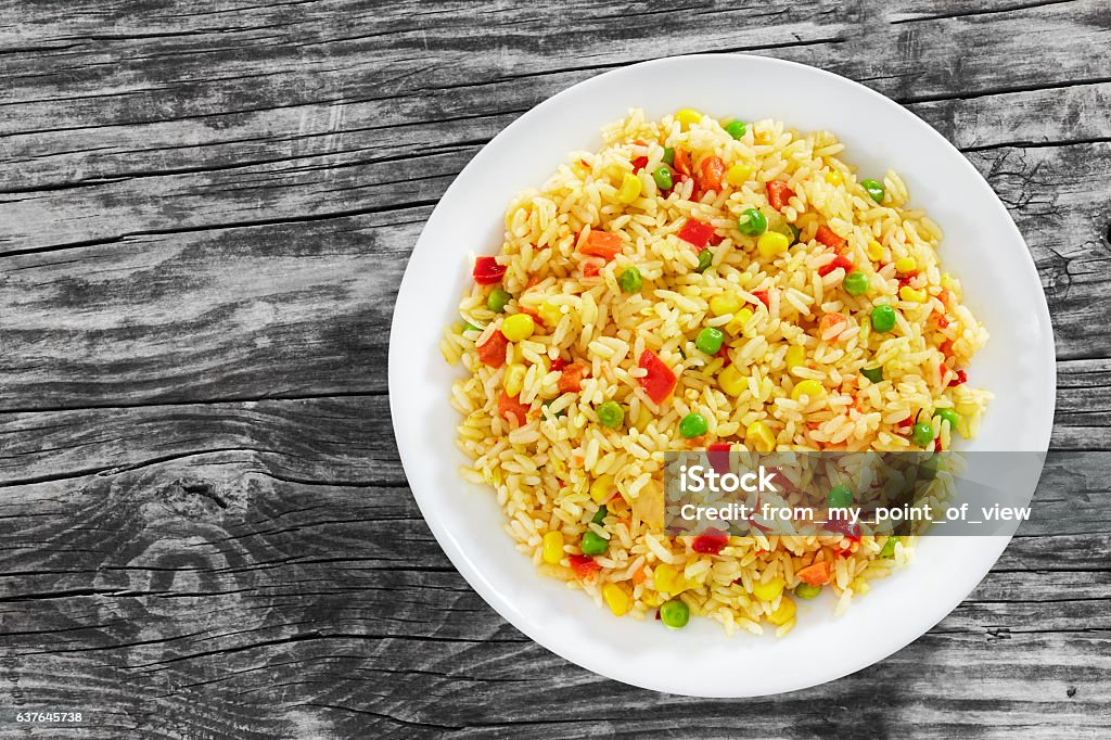 Sweet Corn, red bell pepper, green peas delicious  healthy Risot Sweet Corn, red bell pepper, green peas delicious  healthy Risotto on white plate on old wooden table, view from above Rice - Food Staple Stock Photo