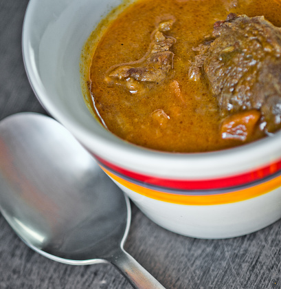 cup of tasty soup, hot and steaming with beef, vegetables, curry, turmeric and clove seeds