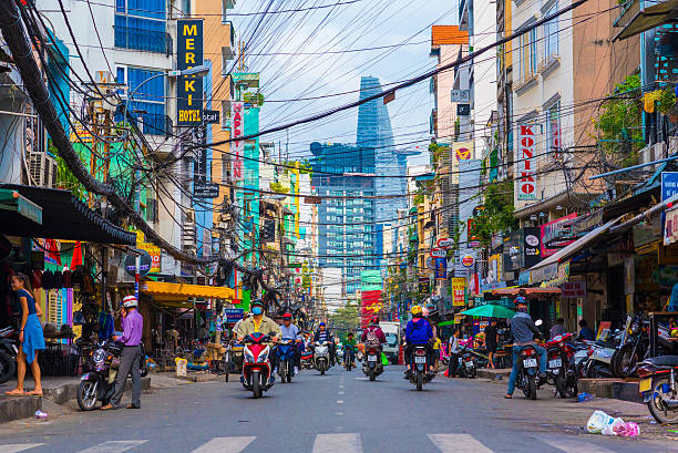 Bui Vien Street, Ho Chi Minh Ho Chi Minh, Vietnam - December 1, 2016: Bui Vien Street (a tourist area). Scooter traffic in Saigon tourist district with Bitexco Financial Tower in background. Many people (unidentified) walk and drive scooters. Many signboards of hotels and hostels. ho chi minh city stock pictures, royalty-free photos & images