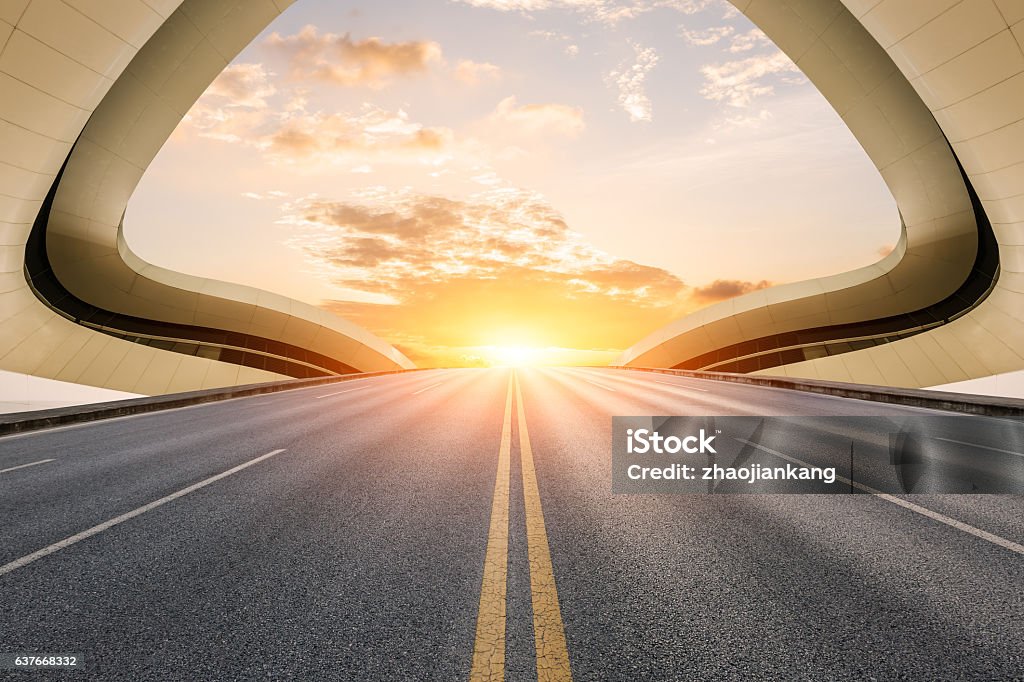 Asphalt road in front of modern bridge construction Asphalt road and modern bridge construction at sunset Bridge - Built Structure Stock Photo