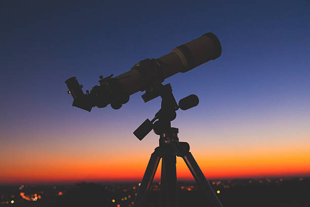 istock Silhouette of a telescope with de-focused city lights. 637668546