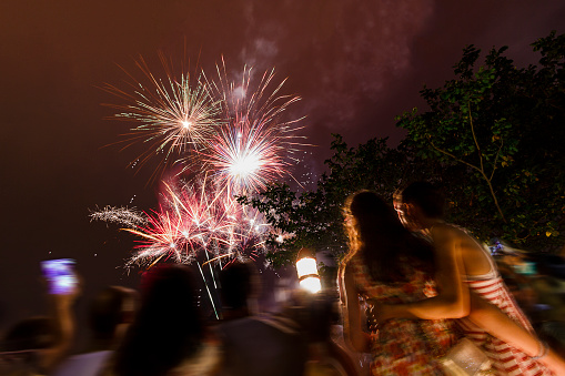 A DSLR Canon long exposured photo of two brazilian littles sisters hughing each other while watching  the fireworks on New Year's Day in Copacaban Beach in Rio de Janeiro, Brazil.