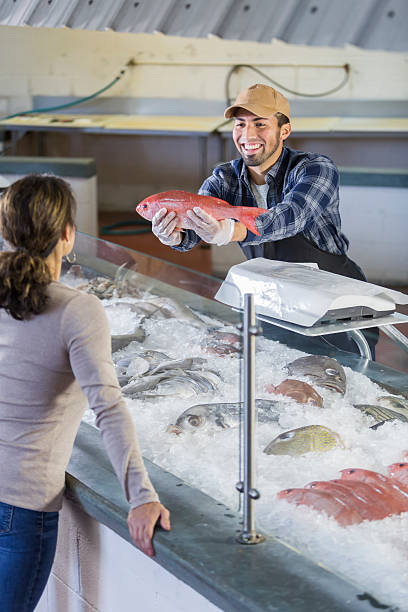 istock Worker in seafood market helping customer 637672202