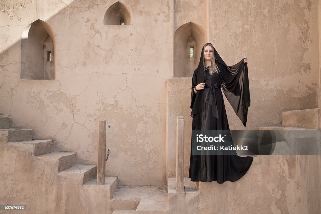 Young Woman in an abaya in Jabrin castle young woman in  traditional dress (abaya) in Jabreen Castle in Oman Abaya - Clothing Stock Photo