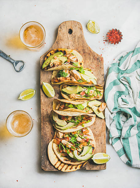Corn chicken and avocado tortillas on wooden board, top view