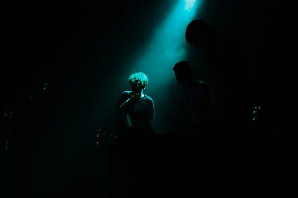 Teenage music band from Denmark. Tree young boys make music on stage in Denmark. Shoot by aqua blue spotlights.