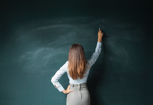 Back view of a businesswoman about to write something on a blackboard