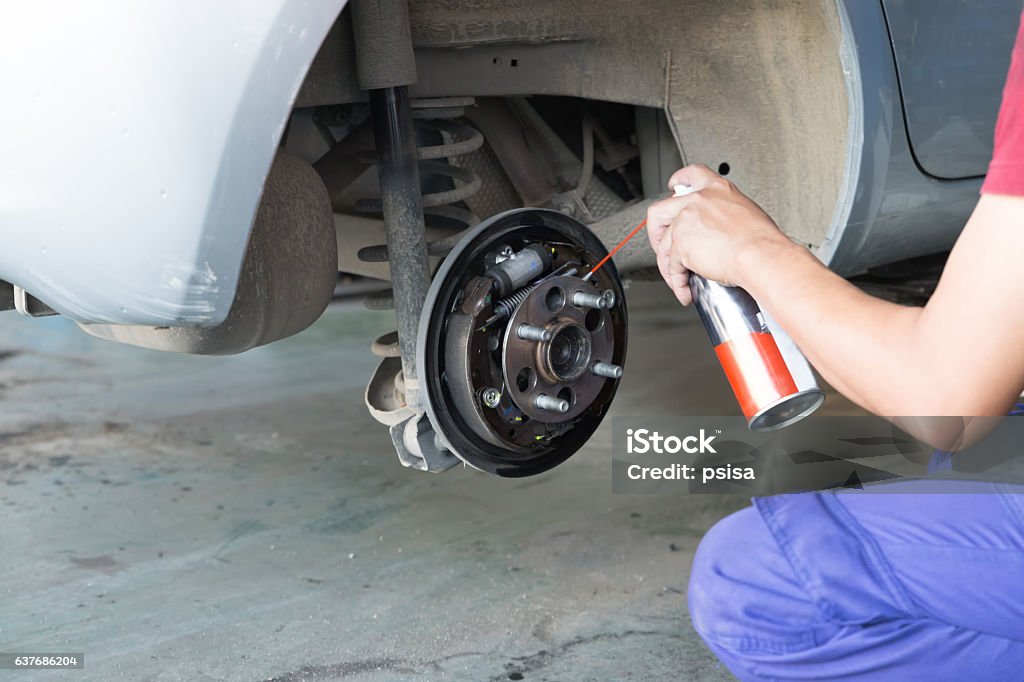 mechanic spray chemical to clean brake mechanic spray chemical to clean brake during tyre replacement service Brake Stock Photo