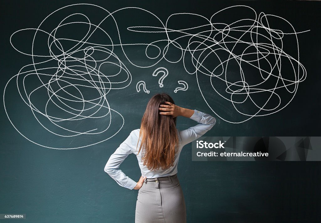 Businesswoman Mess on Blackboard Confused business woman staring at scribble on blackboard Confusion Stock Photo